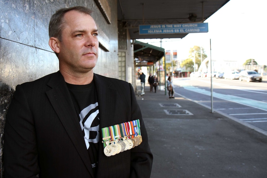 Former Australian Army Captain Jason Scanes stands in a street.