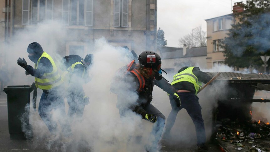 Protesters construct a make-shift barricade in Bourges with bins and a shelter turned into its side.