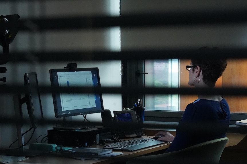 A woman sitting at a desk works on her computer