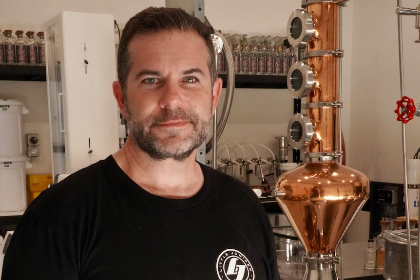 A man stands in a distillery.