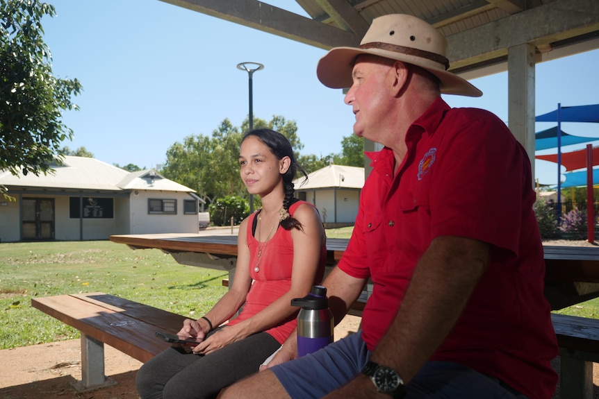 Caitlyn Roe and Alan Gray sit together on a picnic table.