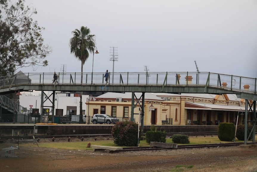 A rail pedestrian bridge with a train station in the background