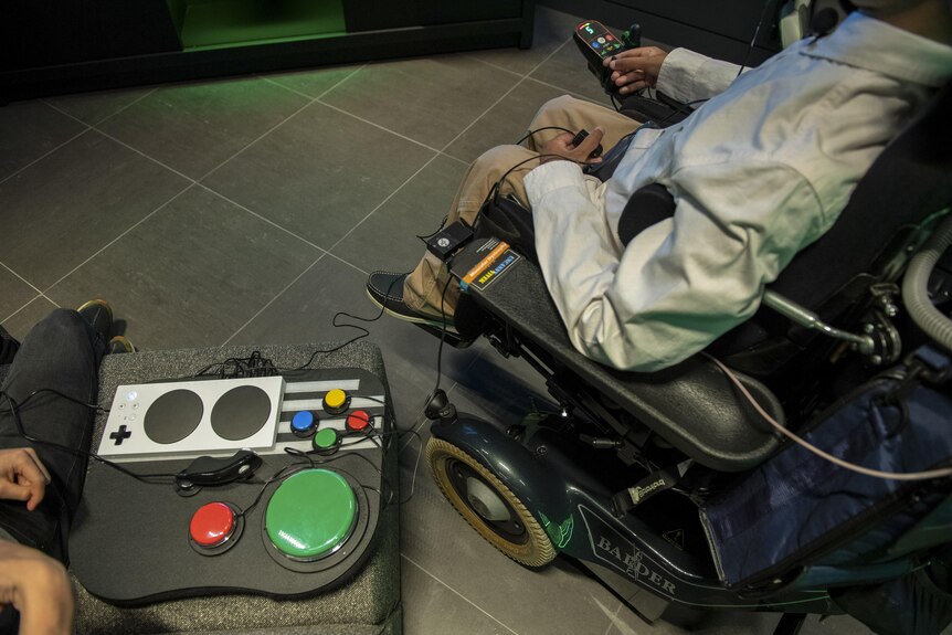 An adaptive Xbox console, and a person in a power wheelchair next to it.