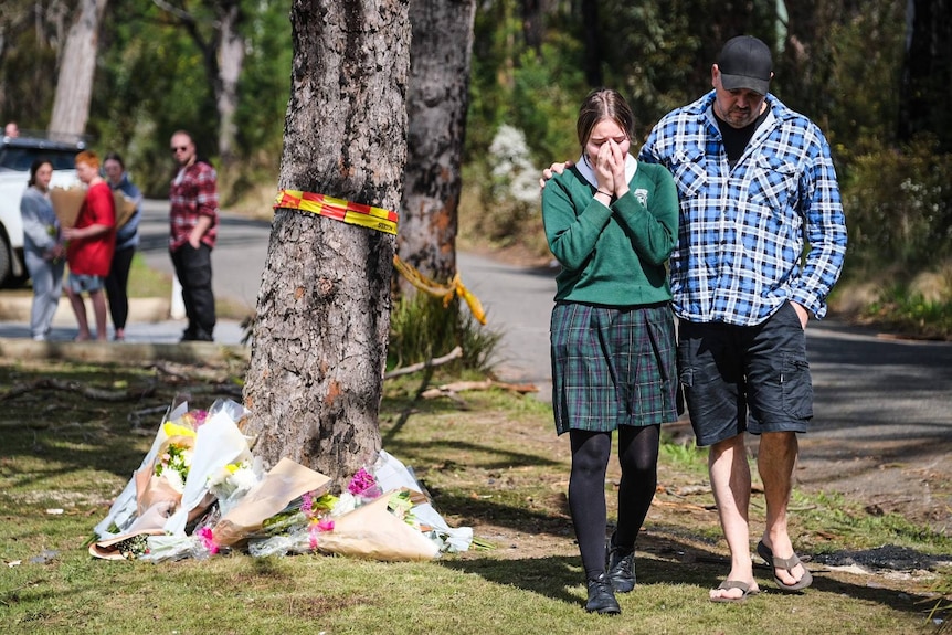 A girl in school uniform cries at a car crash scene