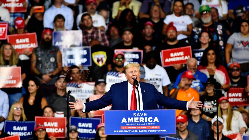 Supporters look on as former US President Donald Trump speaks during a rally