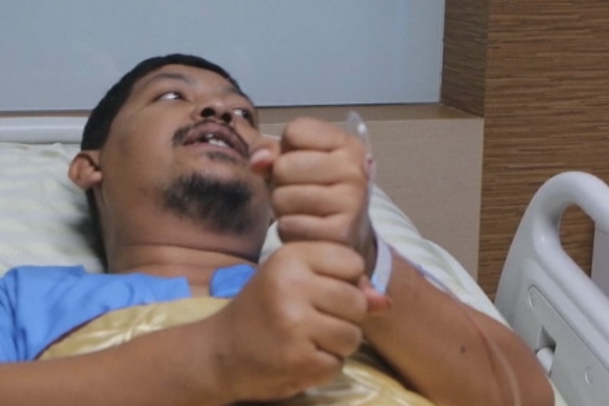 A man lying in a hospital bed.