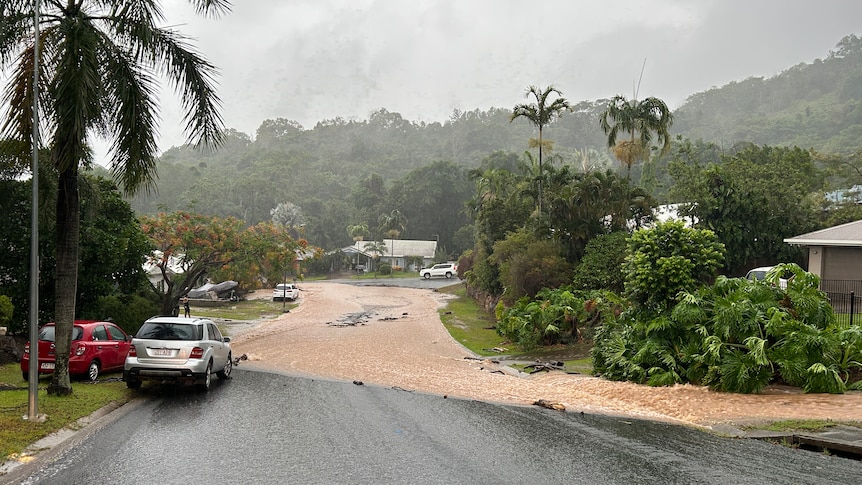 Brown water flows down a street in Cairns on a rainy day.
