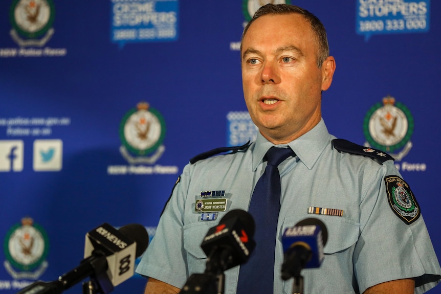 A police officer speaks at a lectern with media microphones in front of him.