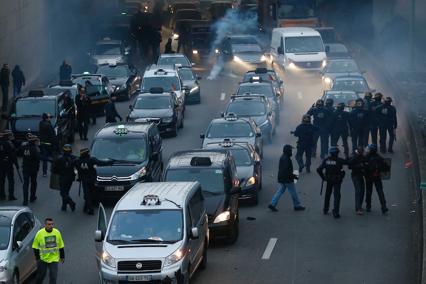 Riot police detain a man during a demonstration by taxi drivers on the Paris ring-road.