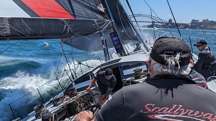 Yacht racing with Sydney Harbour Bridge in background.