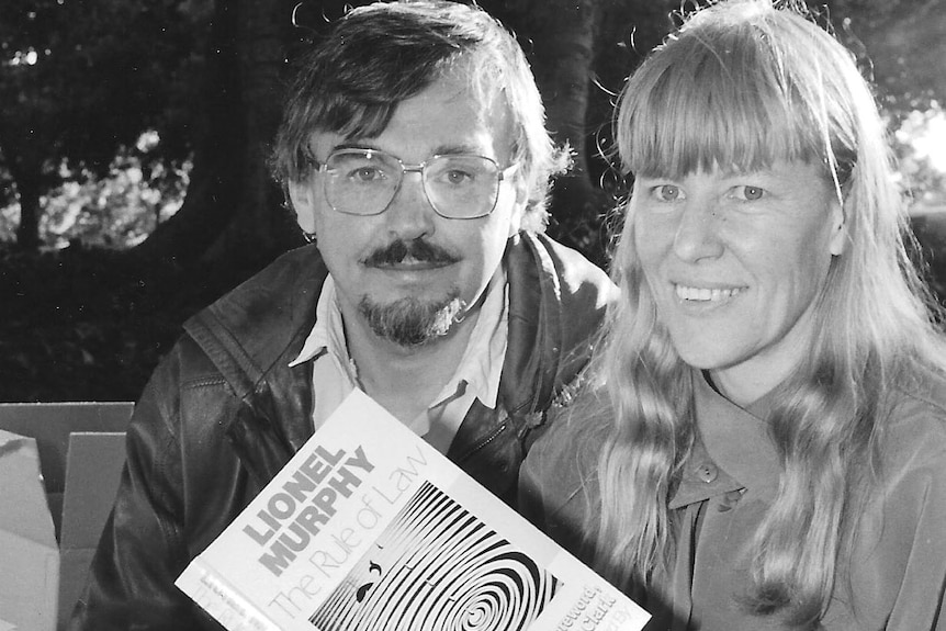 Black and white photo of a man and woman holding a book about Lionel Murphy's judgements.