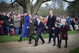Princess Catherine wearing a blue coat holds her daughters hand next to William and sons George and Louis