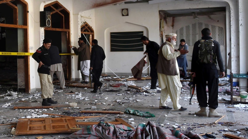 Officers survey the damage after militants stormed Pakistan mosque