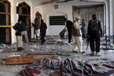 Officers survey the damage after militants stormed Pakistan mosque