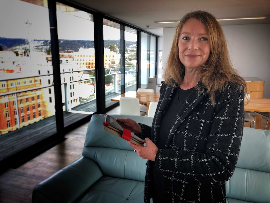 Real estate agent Robbie Yeoland stands in an apartment, with Hobart in the background.