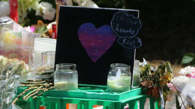 Flowers, balloons, and a card with a purple heart and the words 'our hearts rip' are seen at a memorial for Aiia Maasarwe.