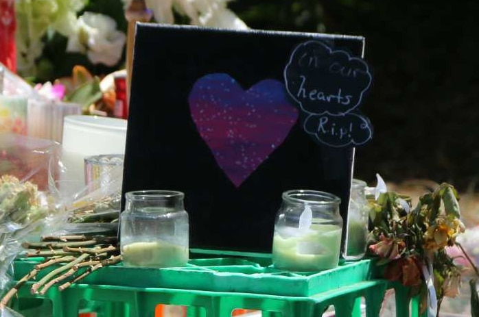 Flowers, balloons, and a card with a purple heart and the words 'our hearts rip' are seen at a memorial for Aiia Maasarwe.