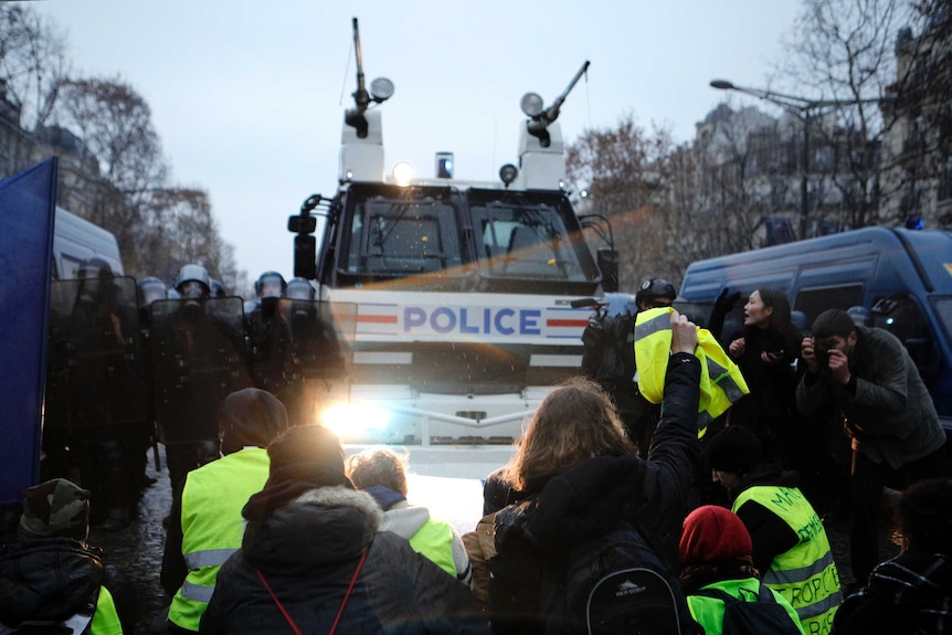 Demonstrators sit in front of a police water cannon on the Champs-Elysees avenue.