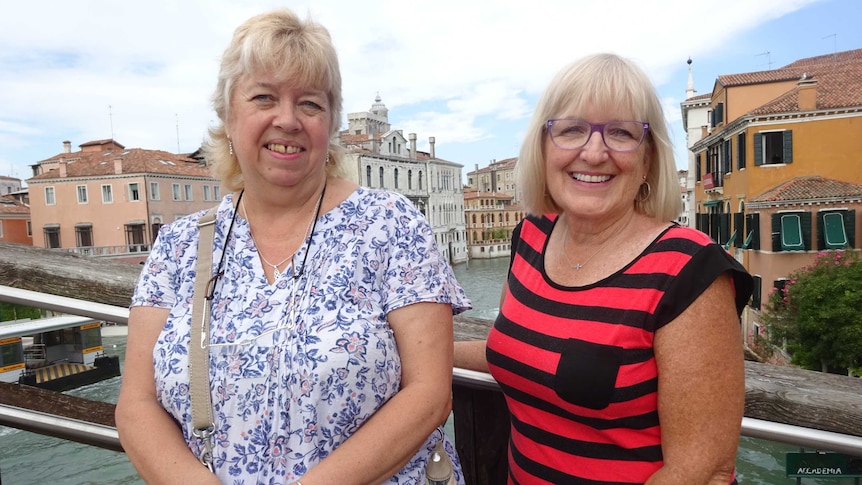 Two women posing with each other in front of canals in Venice.