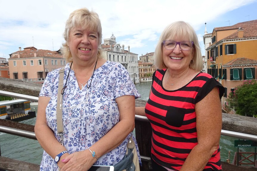 Two women posing with each other in front of canals in Venice.