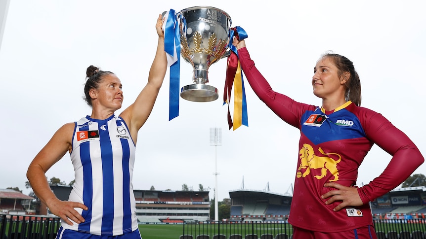 Emma Kearney and Breanna Koenen hold and look at the AFLW premiership cup