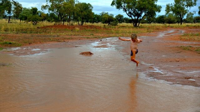 Charlie Kidd jumping in a puddle near Windorah.