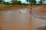 Charlie Kidd jumping in a puddle near Windorah.