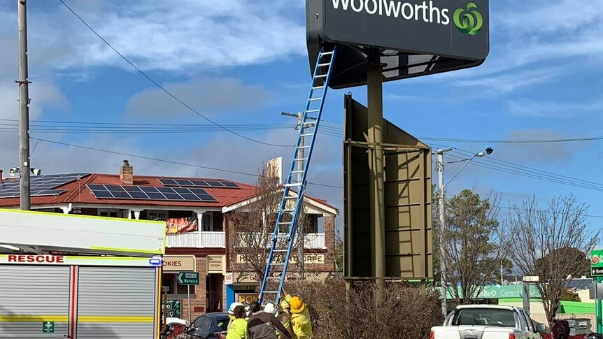 Firefighters hold a ladder under a shopping centre sign