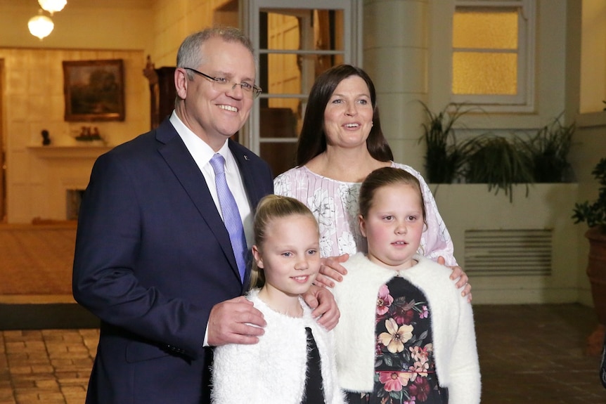 Scott Morrison stands next to his wife, and two young daughters, all smiling at the camera.