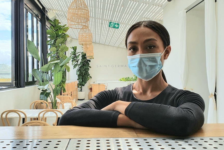 Havana Tan stands inside her restaurant with a face mask on