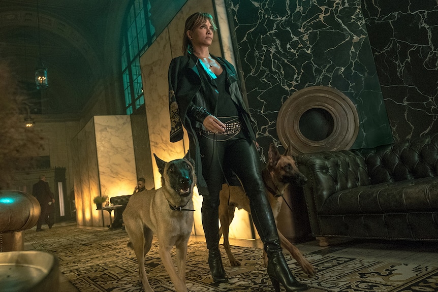 Colour still of Halle Berry walking down through grand lobby accompanied by two Belgian Malinois dogs in John Wick: Chapter 3.