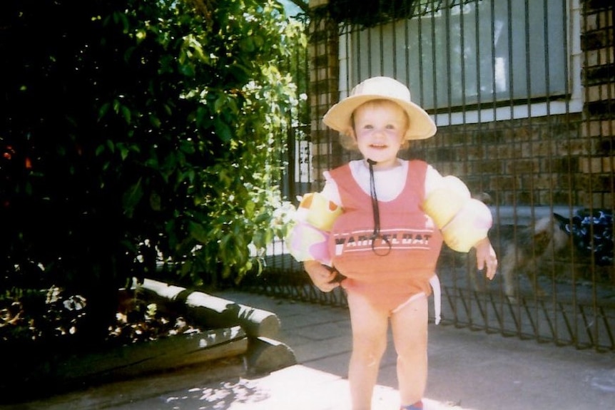 Laura Folbigg wears a hat and floaties outside.