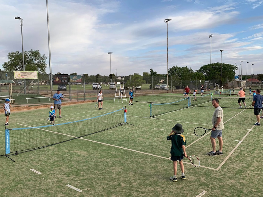 People playing on synthetic grass tennis courts.