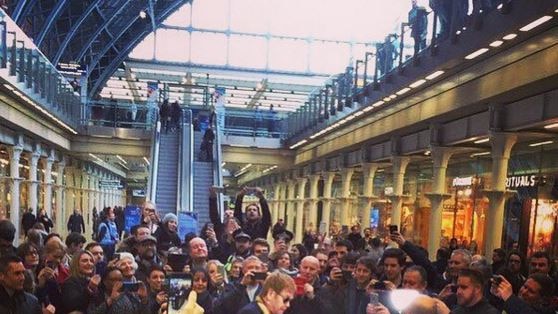 Elton John signs a piano in a packed train station