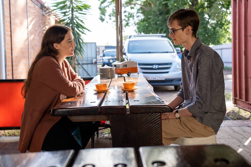 a reporter and Myles Egan, a researcher, having a conversation at a cafe table