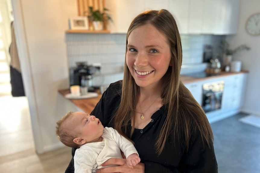 A young mother smiles as she holds her baby