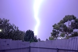 Lighting strike during morning thunderstorm overlooking Morphett Vale in Adelaide, fence at bottom, trees to the side