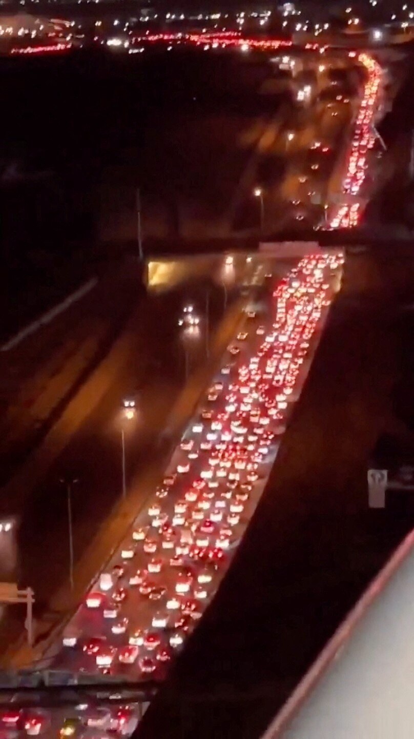 Cars sit gridlocked on a highway at night in a city
