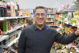Shop owner stadning between grocery aisles 