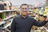 Shop owner stadning between grocery aisles 