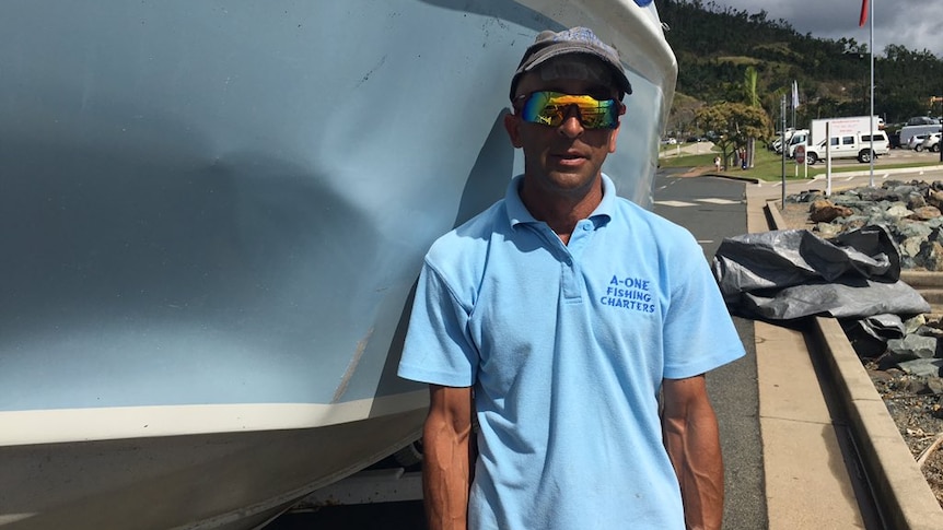 Skipper Oliver Galea, stands besides the boat that was damaged after colliding with a humpback whale.