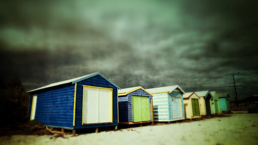 Storm clouds massing behind bayside bathing boxes in Melbourne