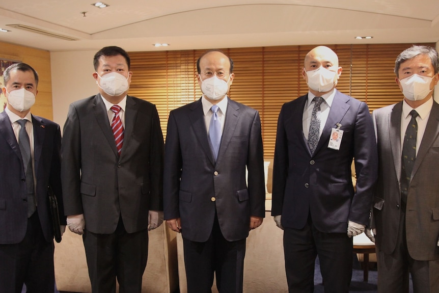 A group of five men wearing masks.
