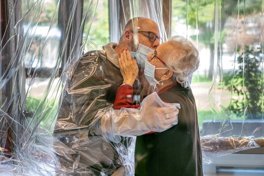 Resident kisses a relative through a plastic sheet installed in a special 'hug room' at a nursing home in Italy