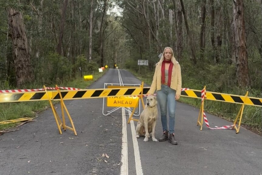 Megalong Valley resident Claudia Abbott stands on a blocked off road with her dog