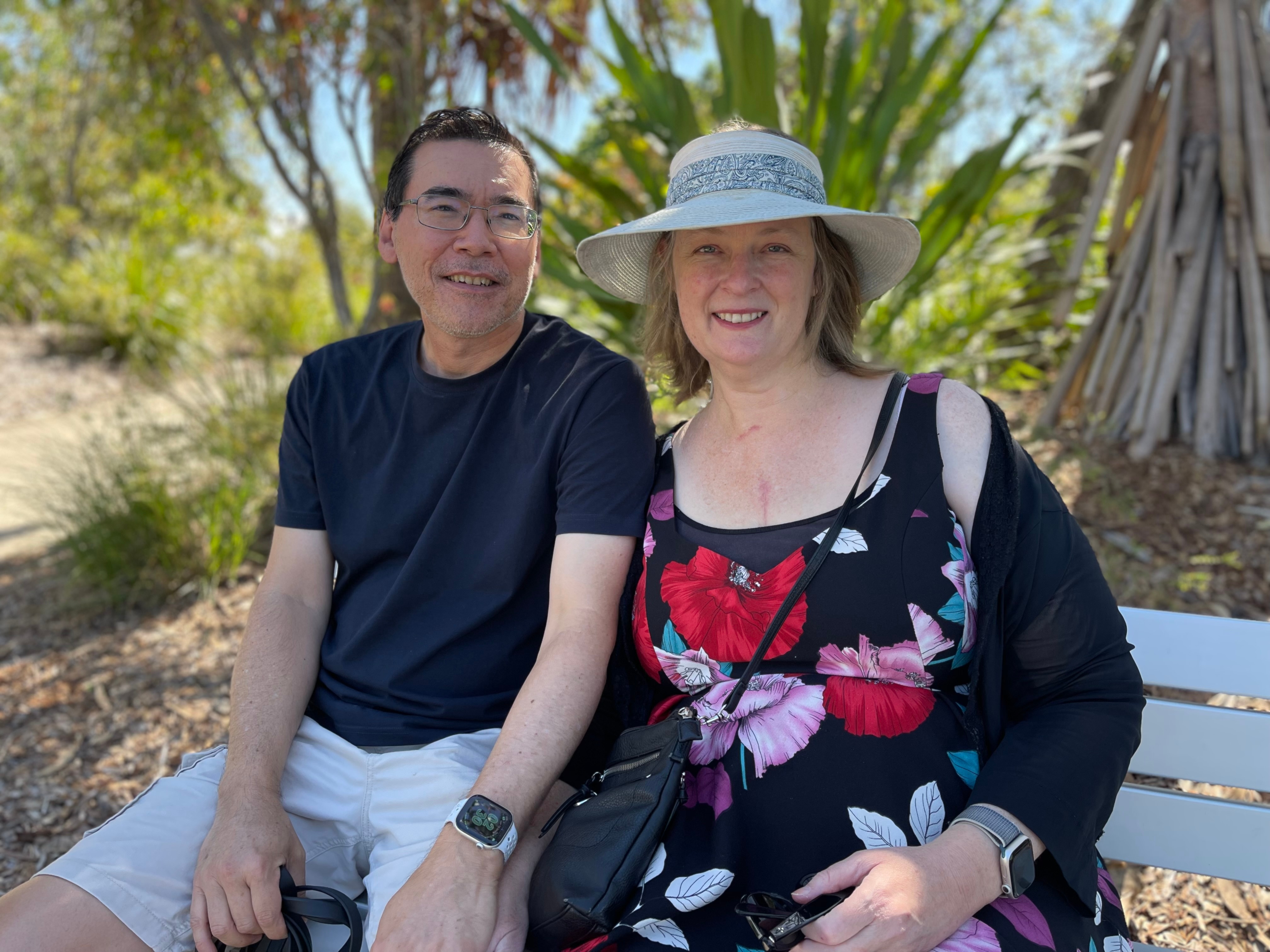 Un hombre de mediana edad y una mujer se sientan en un banco del parque. 