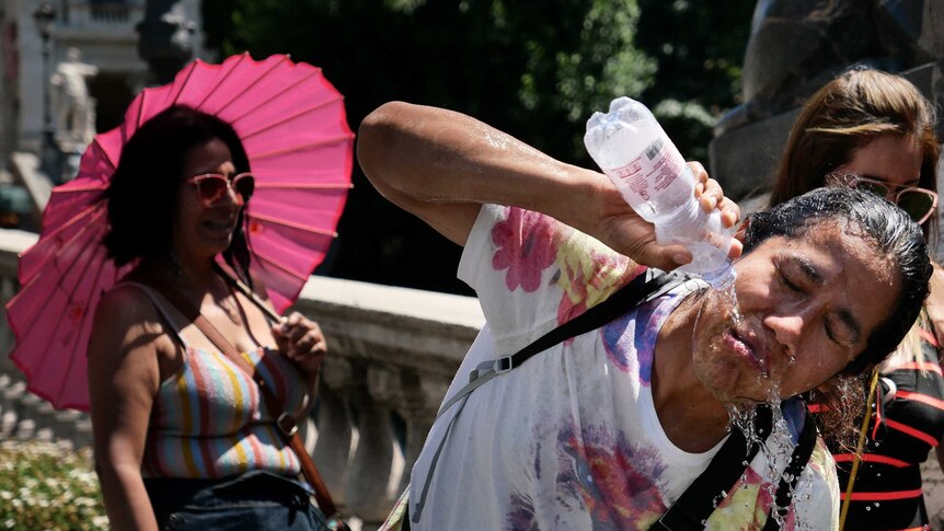 A tourists refreshes by pouring a bottle of water over her face.