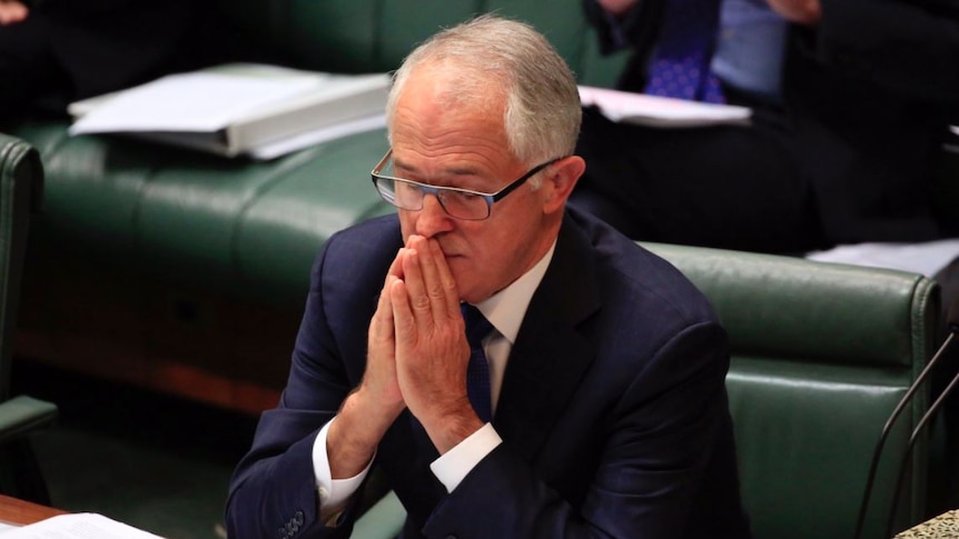 Malcolm Turnbull holds his hands to his lips and closes his eyes as if he were praying during question time.