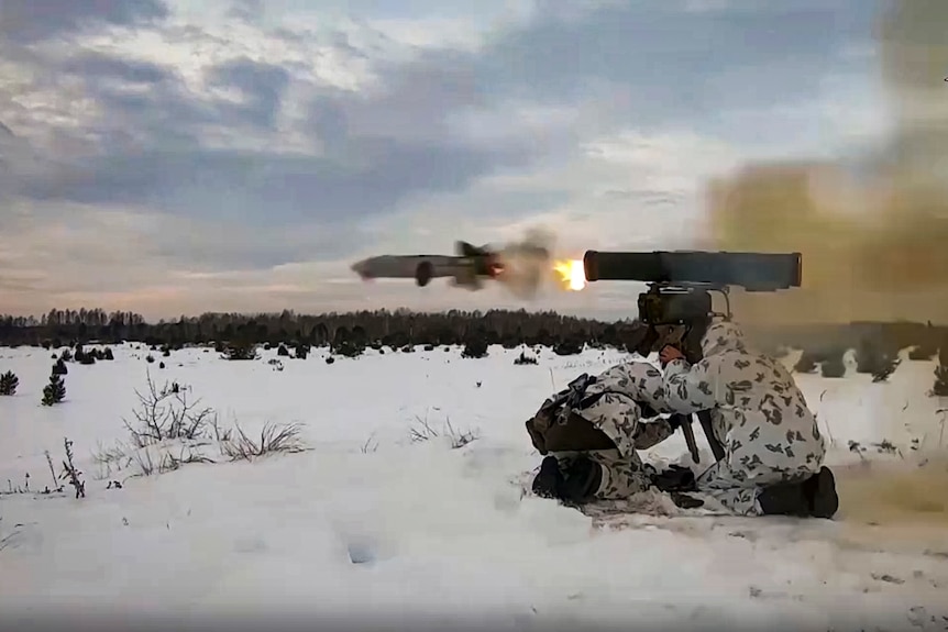 A Russian soldier fires a projectile during drills in Belarus with the ground covered in snow