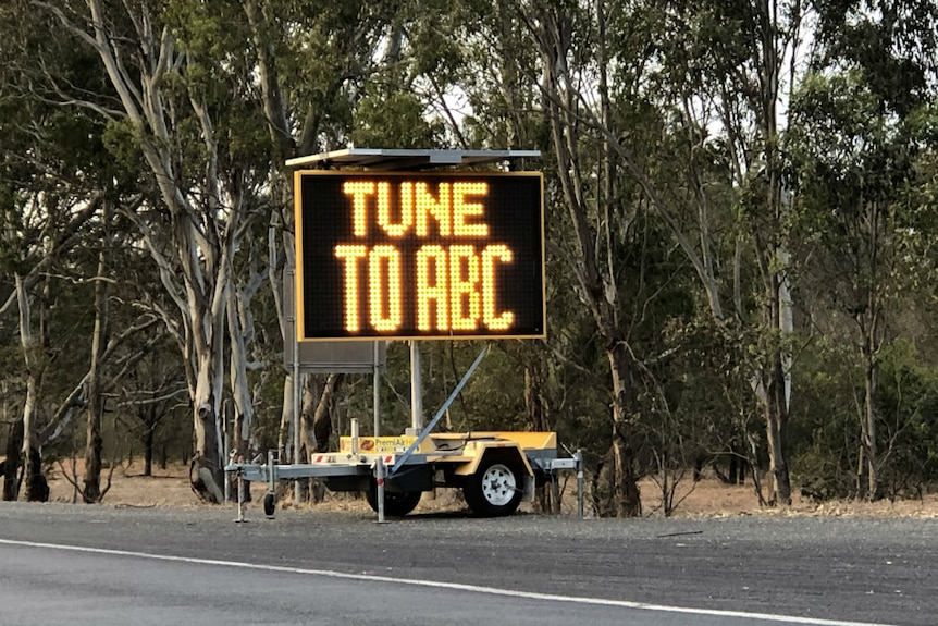 Sign by side of road saying 'tune to ABC'.